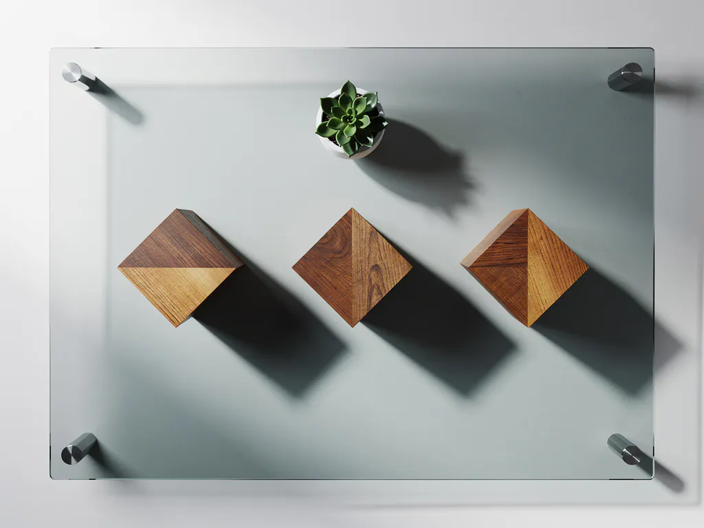 Glazen vergadertafel met drie houten blokken die kwartalen voorstellen, vetplant gepositioneerd volgens gulden snede, schaduwen van donker naar licht